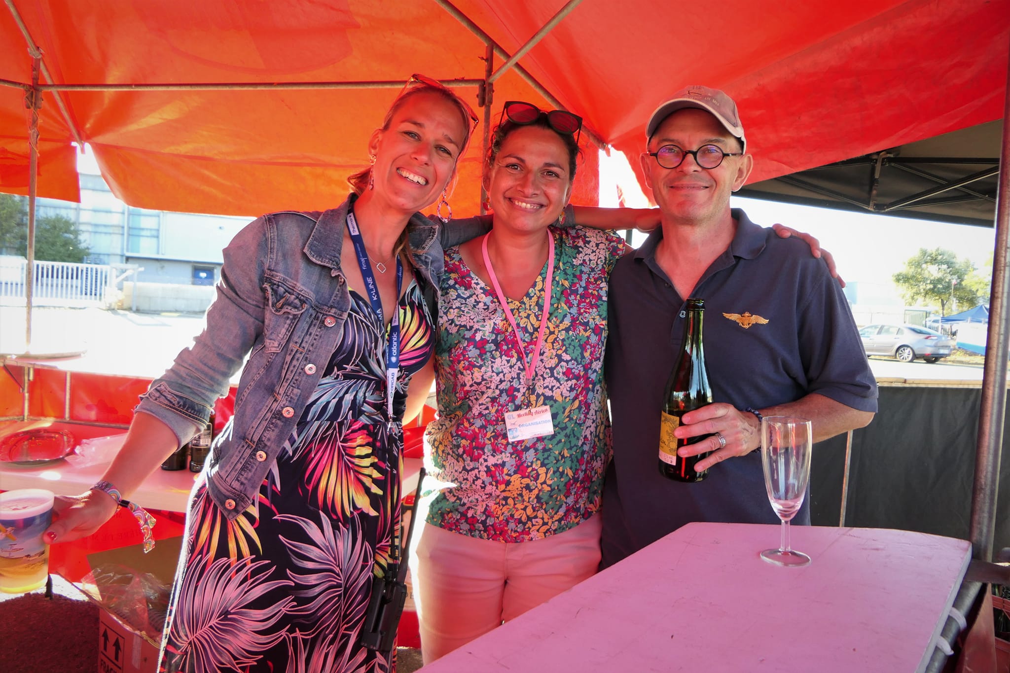 Trois bénévoles de l’Aérodrome Bretagne Atlantique partageant un moment festif sous un chapiteau.