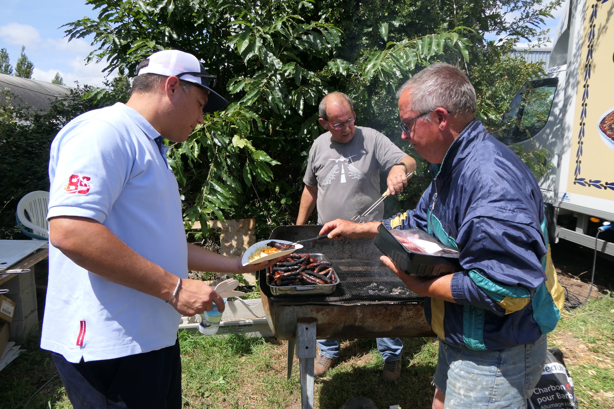 Bénévoles de l’Aérodrome Bretagne Atlantique préparant un barbecue pour un moment de convivialité après une journée d’activités aériennes.