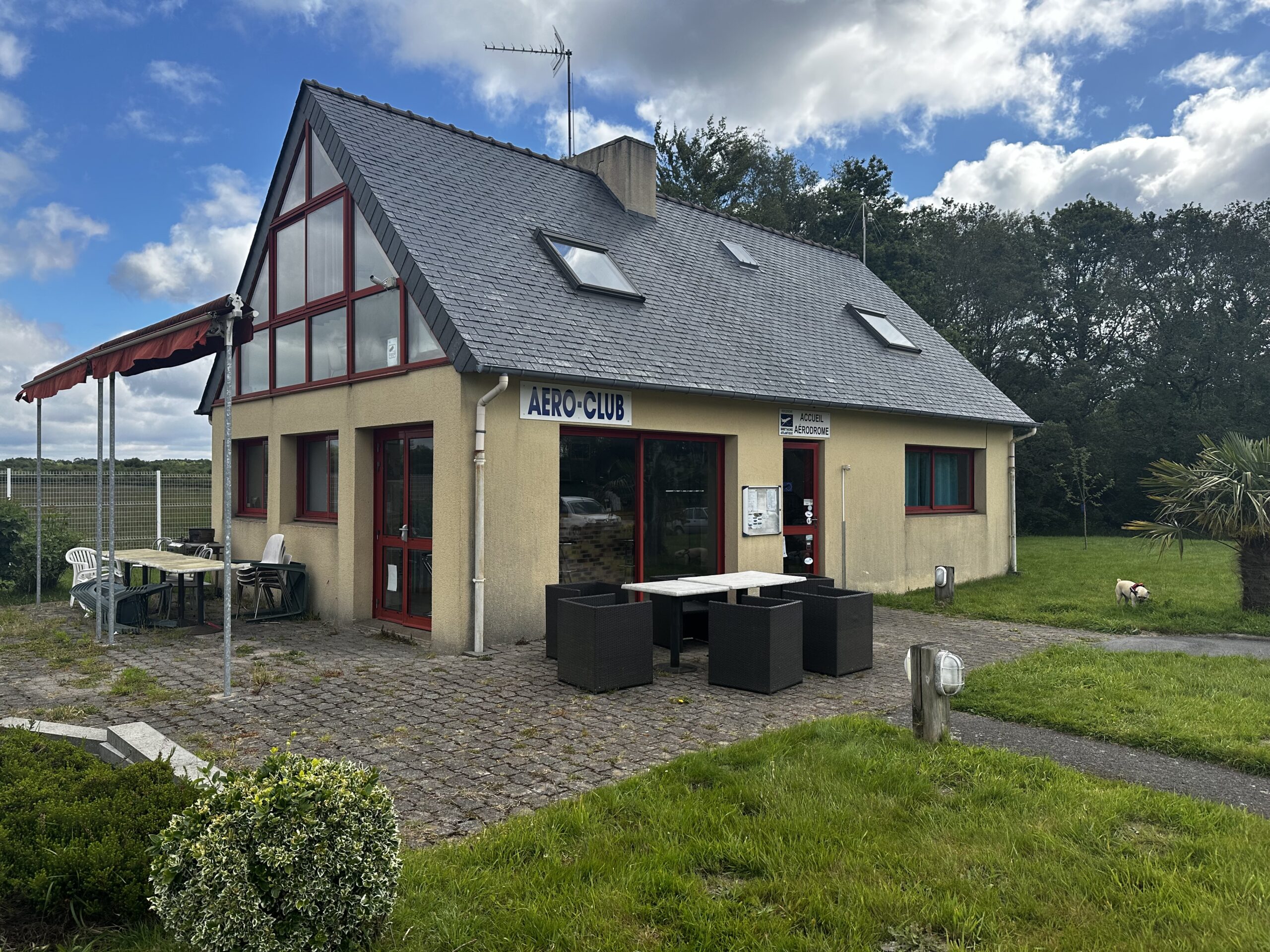 Vue extérieure du Club House de l’Aérodrome Bretagne Atlantique avec terrasse et vue sur les pistes.